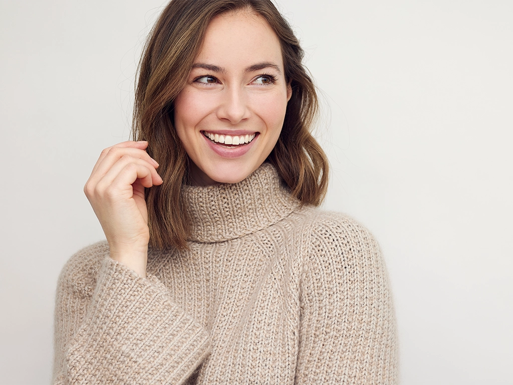 Portrait of happy beautiful woman smiling and standing in a warm sweater