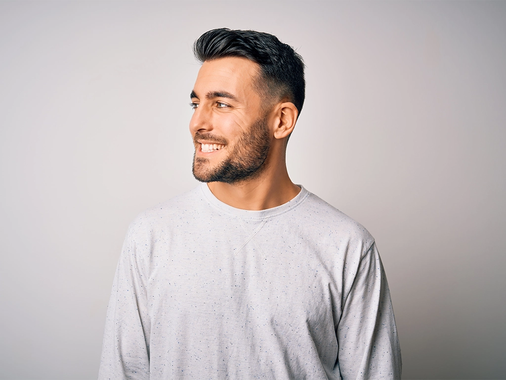 young handsome man wearing casual t-shirt looking away to side with smile on face